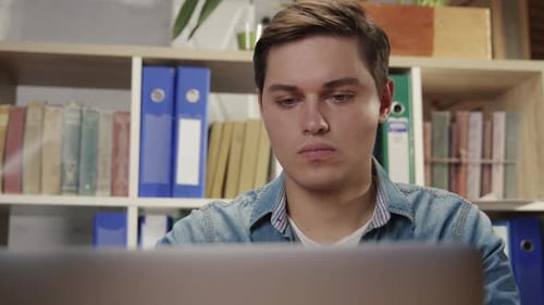 Young Man Working on Laptop at Desk