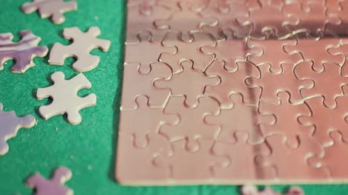 Intelligentes Mädchen in weißem Hemd sammelt ein schwieriges Puzzle, das aus kleinen Teilen auf Holz besteht
