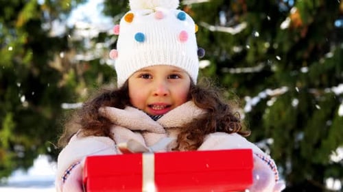 Excited Girl Holding Christmas Present Outside in Winter Snow