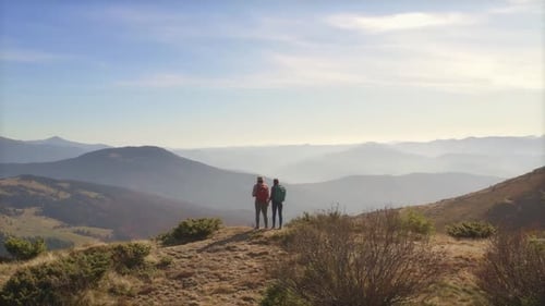 Epische Luftaufnahme eines Wanderpaares mit Rucksäcken auf einem Berggipfel