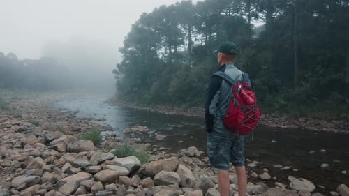 Man hiking in the wild area and tries the water in a river
