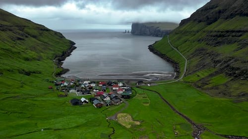 Vue aérienne époustouflante du village de Tjornuvik dans les îles Féroé entouré de falaises majestueuses