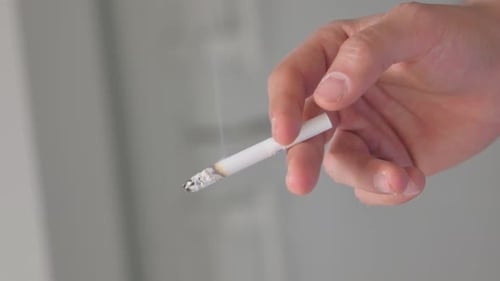 Brennende Zigarette beim Rauchen in der Hand halten, Nahaufnahme