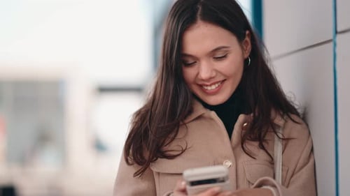Smiling Young Adult Woman Uses Phone