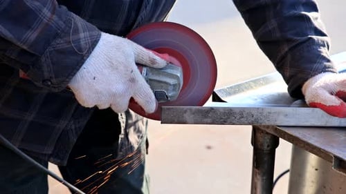 Worker Cutting Metal Using a Grinder with Sparks While Grinding Iron