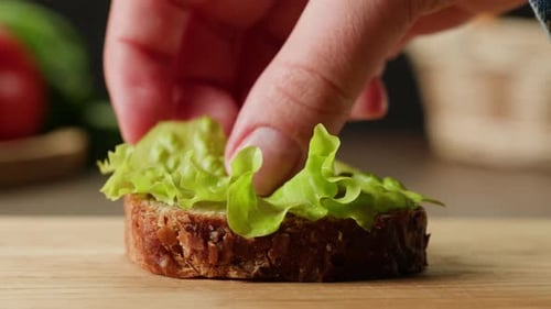 Close Up Hand Preparing Sandwich with Meat Lettuce