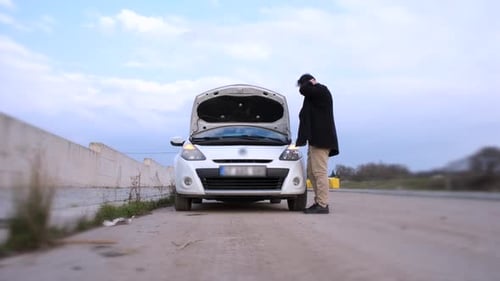 Man Inspecting Car Engine on Rural Road