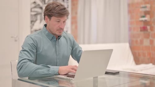 Man Working on Laptop at Glass Desk