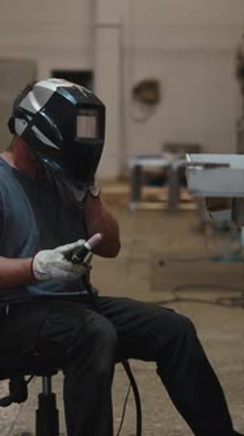 Man Welding Metal in a Factory with Helmet