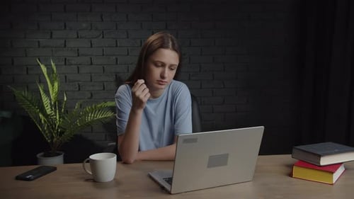 A Tired Woman Sitting at Her Desk is Discussing a Working Project with Colleagues Via Video