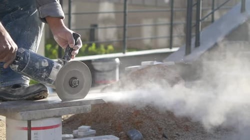 A Man is Using a Grinder to Cut a Piece of Concrete