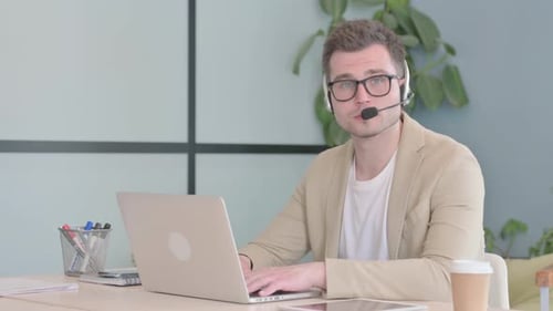Young Businessman with Headset Looking toward Camera in Call Center