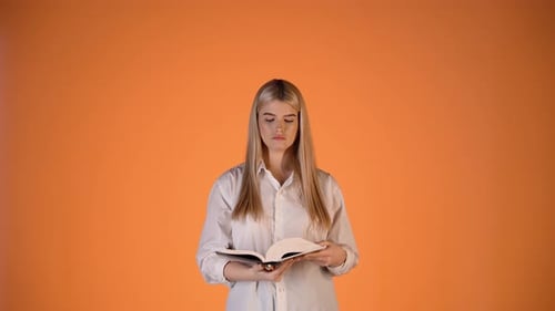 Young Blonde Woman Serious Focused Reading a Book and Turning Pages, Colorful Studio Shot