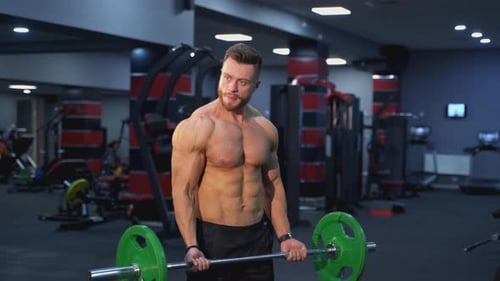 Starker Athlet beim Langhantelheben im Fitnessstudio. Hübscher Mann trainiert mit einer schweren Langhantel
.