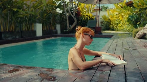 Young Woman Reading Book in Swimming Pool