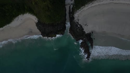 Top down of coastal waves and rocky cliffs in Lombok, Indonesia just after sunset. Aerial.