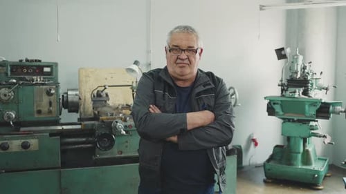 Close-up portrait of an elderly working pensioner locksmith turner in a lathe workshop