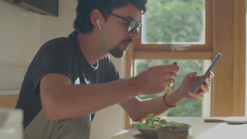 Man Using Smartphone while Eating Meal at Home