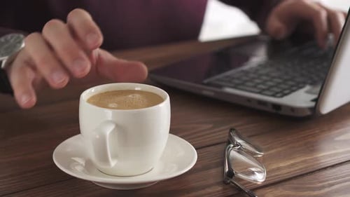 Man Working on Laptop with Coffee on Desk