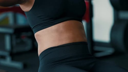 Woman Exercising in Gym Wearing Black Athletic Wear and Focusing on Her Workout Routine