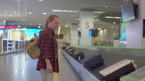 Female tourist with backpack is waiting her luggage in airport