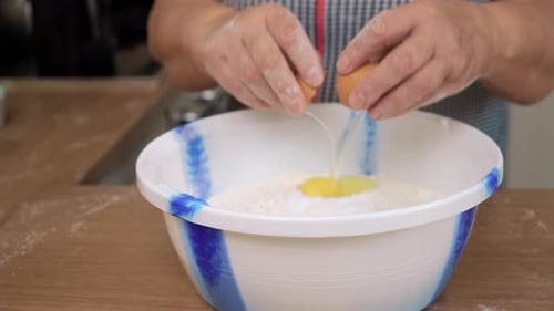 Woman Cracking Eggs into Flour for Baking at Home