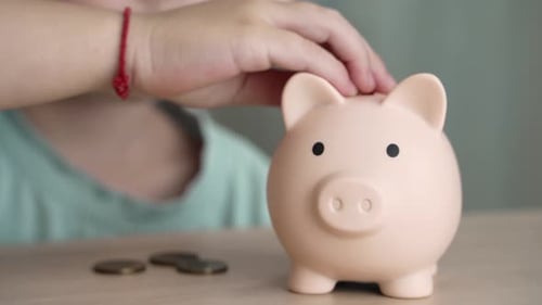 A Young Child Saving Coins In A Piggy Bank For Financial Literacy Training