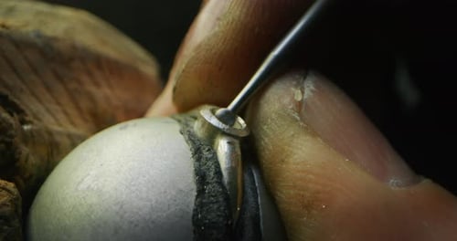 Slow motion macro close up of experienced goldsmith working on a handmade jewelry ring with precio