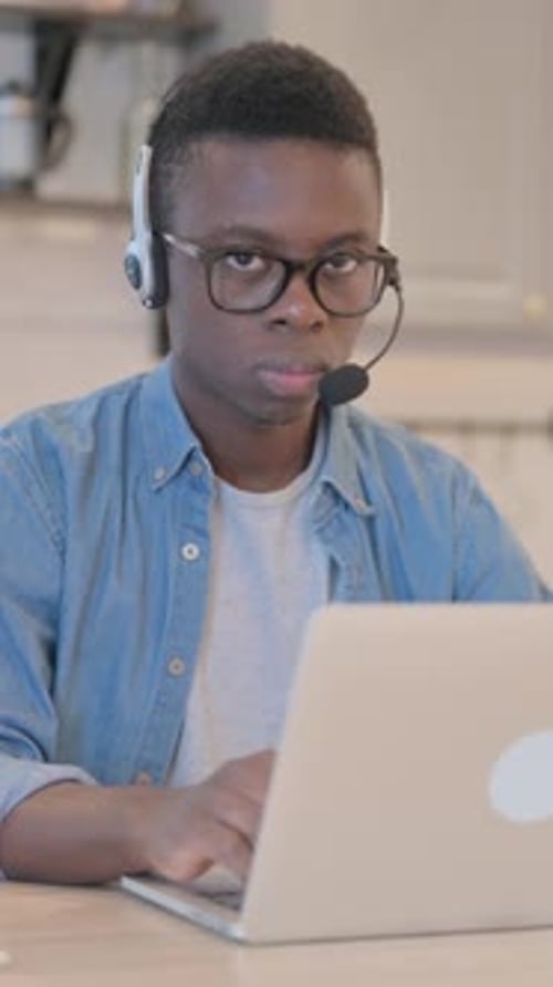 Young African Man with Headset Looking toward Camera in Call Center, Vertical Video