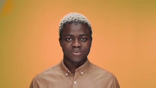 Portrait of smiling young adult against orange background
