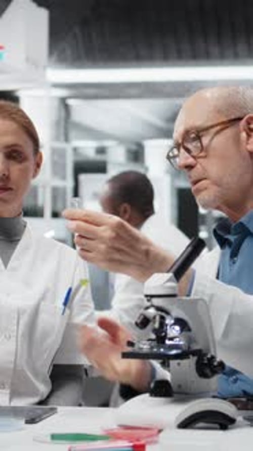 Chef d'équipe du laboratoire vidéo vertical enseignant à un stagiaire l'analyse des propriétés des polymères liquides