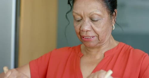 En se concentrant et en ajustant la prise, les mains du cuisinier mélangent la salade rotini dans un bol en verre pour bien mélanger