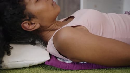 Mulher afro-americana se deita em um tapete espinhoso para massagear as costas