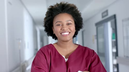 Smiling Woman in Scrubs in Hospital Hallway