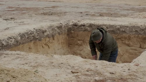Man Digging a Deep Hole in the Ground at a Construction Site During Daylight