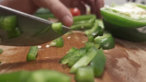 Close-up of cutting green bell peppers into small pieces with a knife