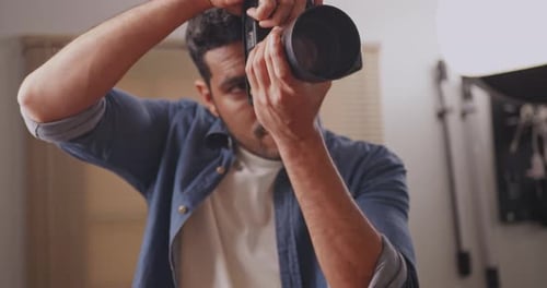 Professional male photographer working in studio. Photographer shooting model with flashlight.