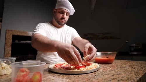 Koch bereitet eine Frischtomaten-Käsepizza mit Champignons zu