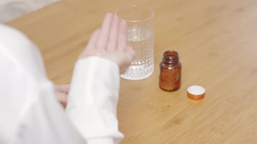 Woman Taking Pills With Water in a Home Setting