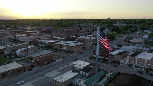 American Flag Waving Over Small Town at Sunrise