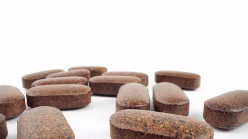 Brown oblong pills on a white background