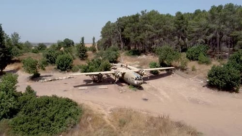 aerial slow turning drone shot of an old dismantled army plane monument placed on an empty dirt fiel