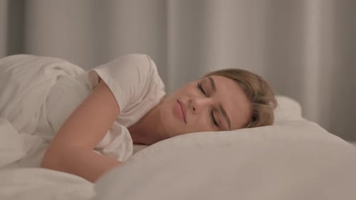 Vue latérale d'une jeune femme qui tousse alors qu'elle est allongée dans son lit