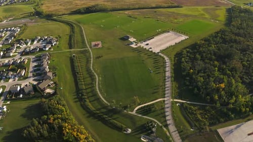 Circling birds eye view of a beautiful lush green soccer park with walking paths and play structures