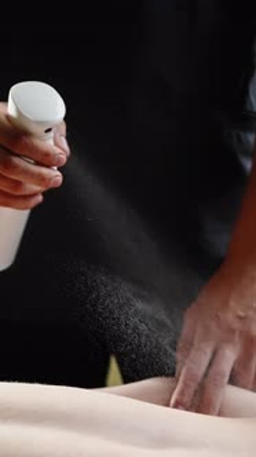 Close-up de um terapeuta profissional de spa borrifando as costas nuas de um cliente com a preparação de spray hidratante