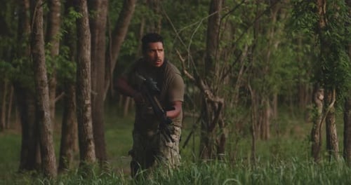 Hispanic Military Man In Camouflage With Combat Assault Rifle Watching Out For Rivals In Forest Whil