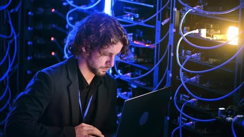 Man Working on Laptop in Server Room