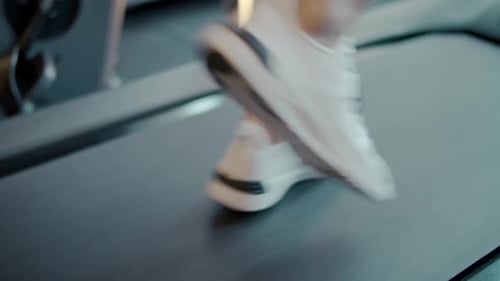 Unrecognizable bodybuilding man's feet doing cardio workout on treadmill at gym