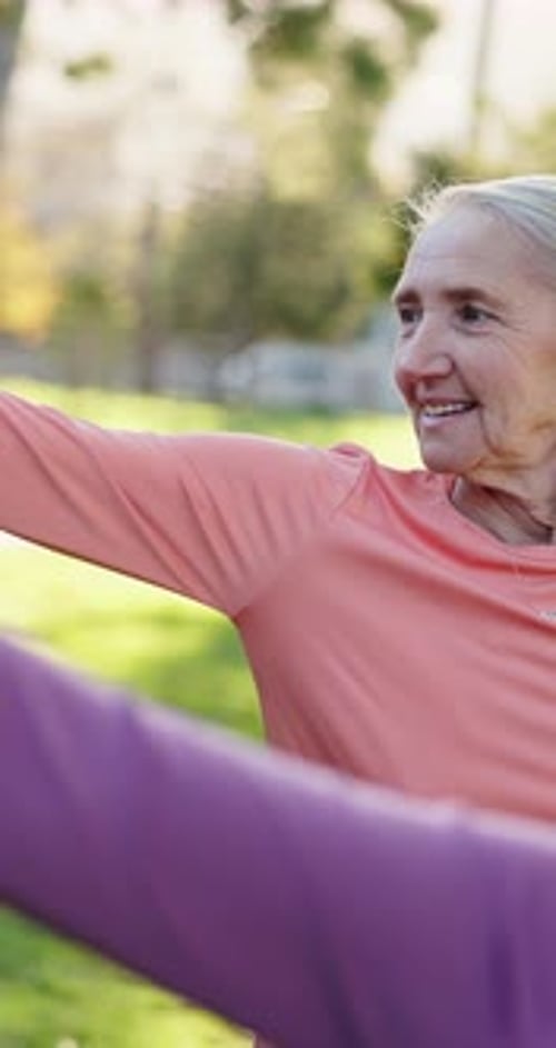 Mature Women Stretching Arms in Park on Sunny Day