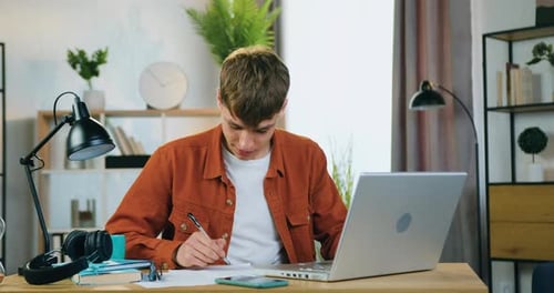 Young Adult Studying at Desk with Laptop
